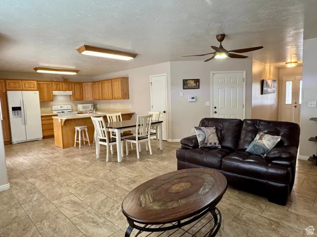 Living room with a ceiling fan, a textured ceiling, and baseboards
