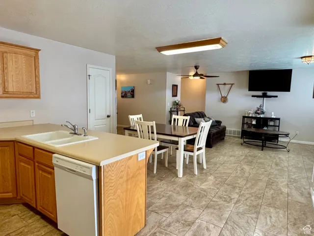 Kitchen with dishwasher, a sink, light countertops, open floor plan, and a textured ceiling