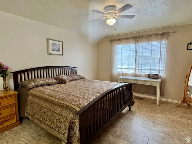 Bedroom with a textured ceiling and a ceiling fan