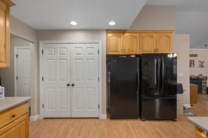 Kitchen with light wood-style flooring, freestanding refrigerator, light countertops, and recessed lighting