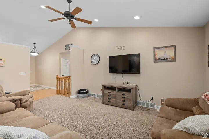 Living area featuring a ceiling fan, baseboards, lofted ceiling, recessed lighting, and carpet floors
