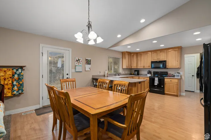 Dining room featuring recessed lighting, a chandelier, light wood finished floors, vaulted ceiling, and baseboards