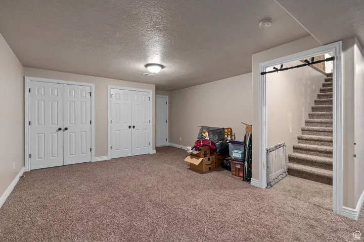 Rec room featuring carpet, a textured ceiling, and baseboards