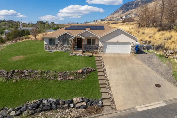 View of front facade with a porch, roof mounted solar panels, concrete driveway, a garage, and a front lawn