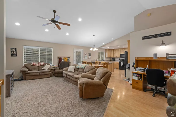 Living room featuring vaulted ceiling, light wood-style floors, an office area, recessed lighting, and a ceiling fan