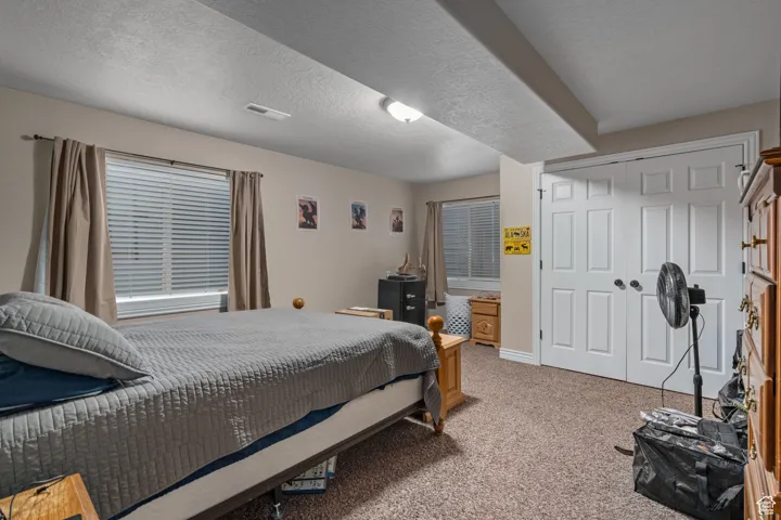 Carpeted bedroom featuring a textured ceiling, a closet, and baseboards