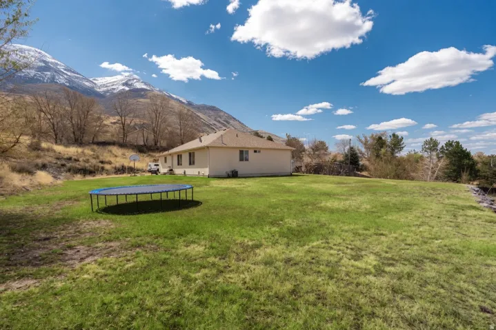 View of green lawn featuring a trampoline and a mountain view