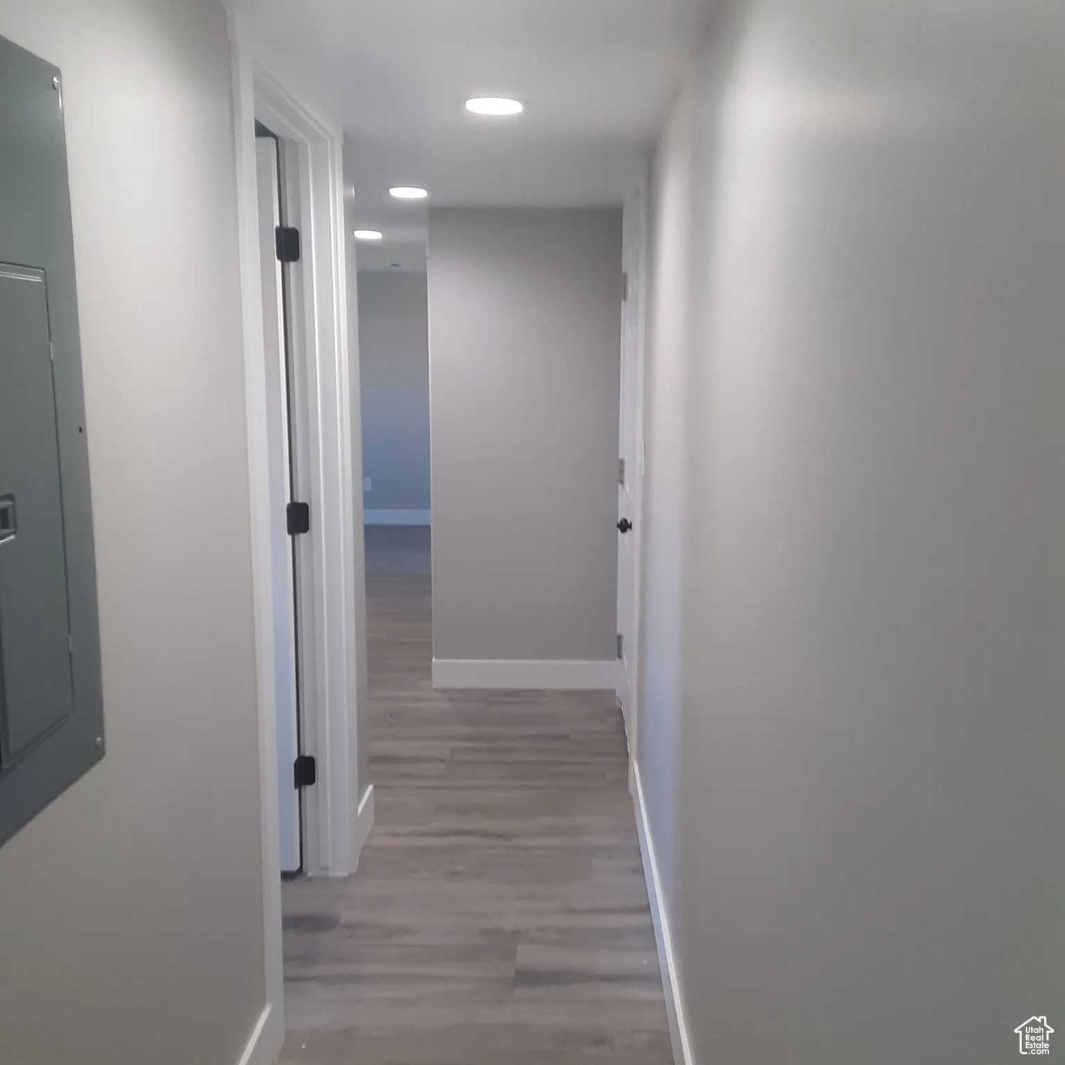 Corridor featuring baseboards, wood finished floors, recessed lighting, and electric panel