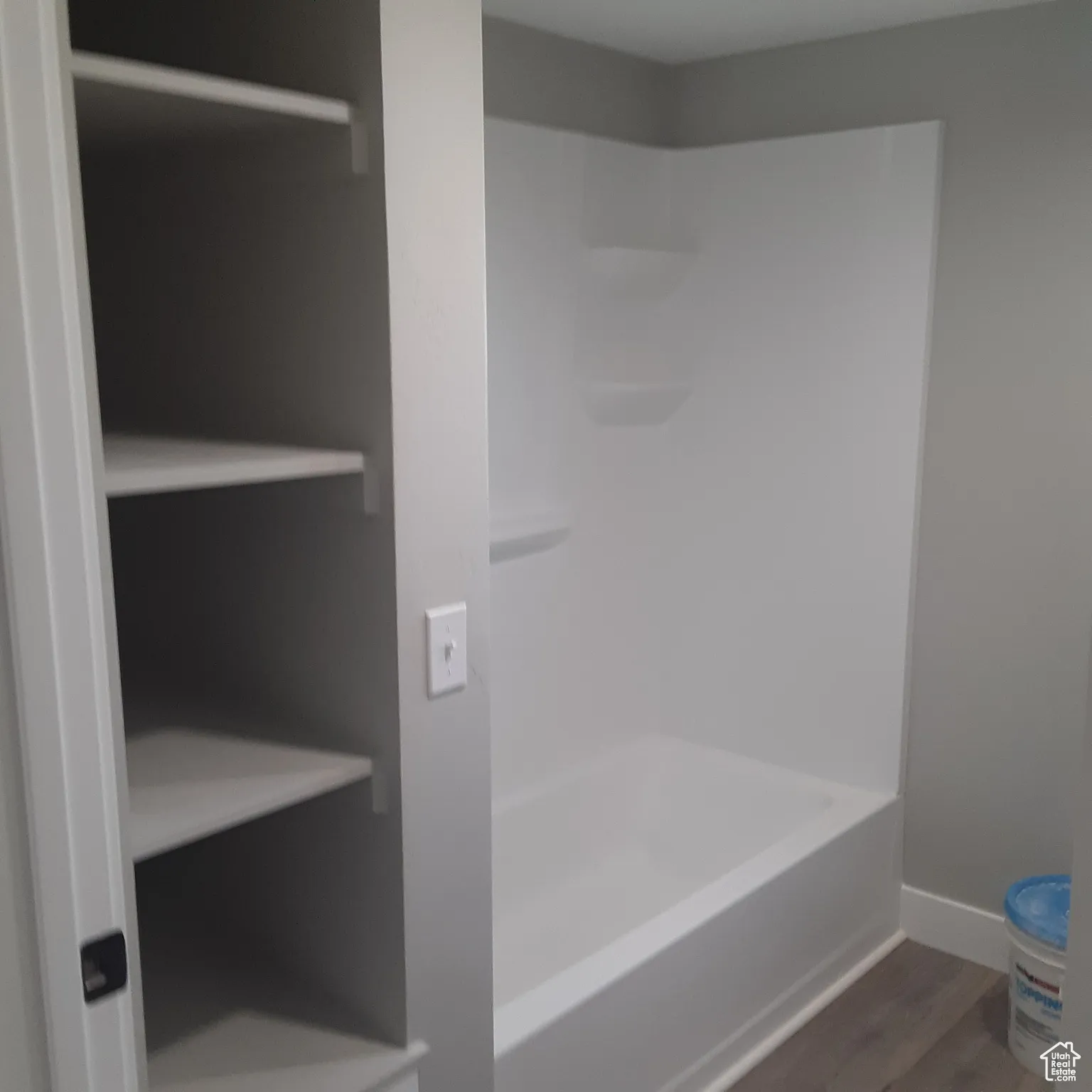 Full bathroom featuring wood finished floors, baseboards, and shower / tub combination