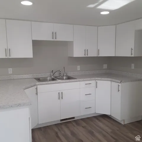 Kitchen featuring a sink, recessed lighting, dark wood-style floors, white cabinetry, and light countertops