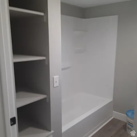Full bathroom featuring wood finished floors, baseboards, and shower / tub combination