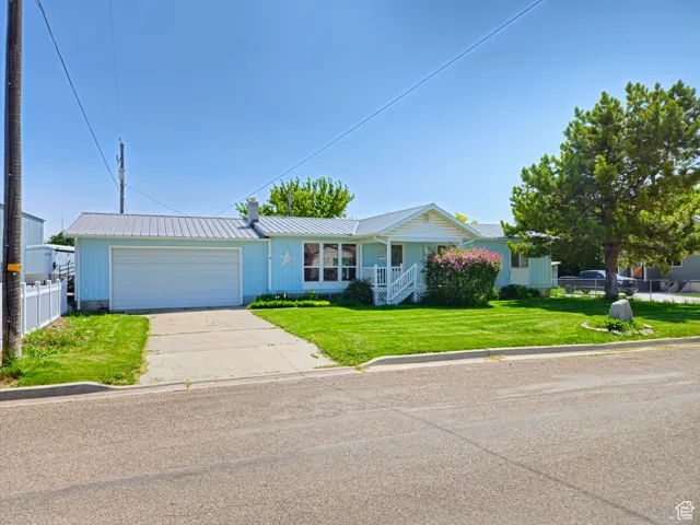 Ranch-style house with a garage, driveway, and metal roof