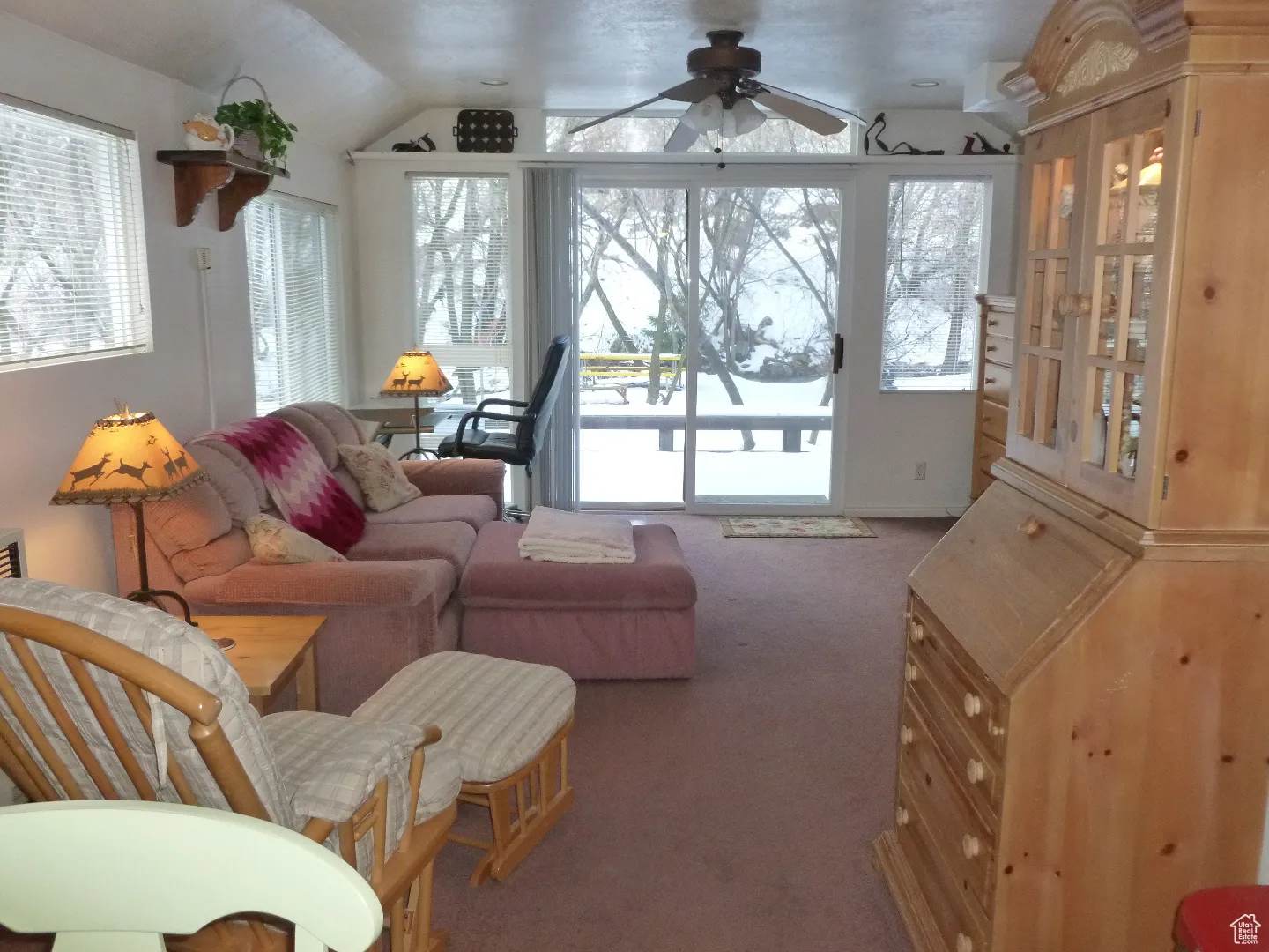 Carpeted living area with ceiling fan and vaulted ceiling