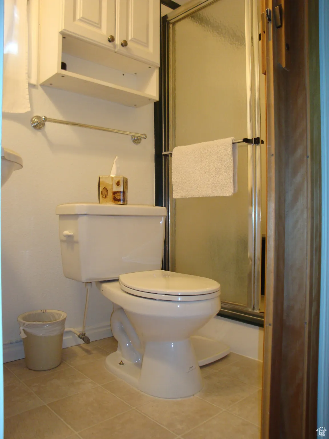 Bathroom featuring a shower stall, toilet, tile patterned flooring, and baseboards