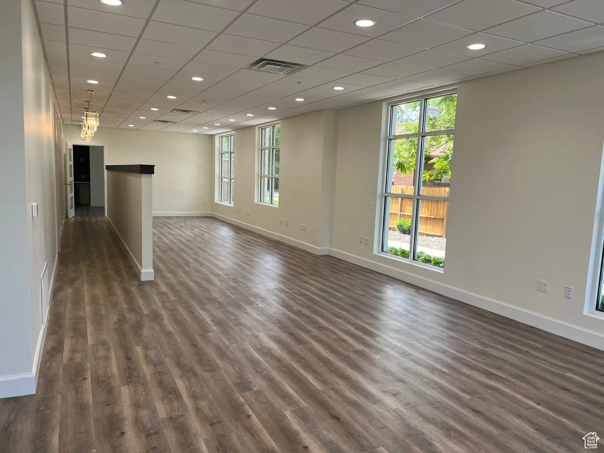 Spare room with plenty of natural light, baseboards, dark wood-style floors, recessed lighting, and a paneled ceiling