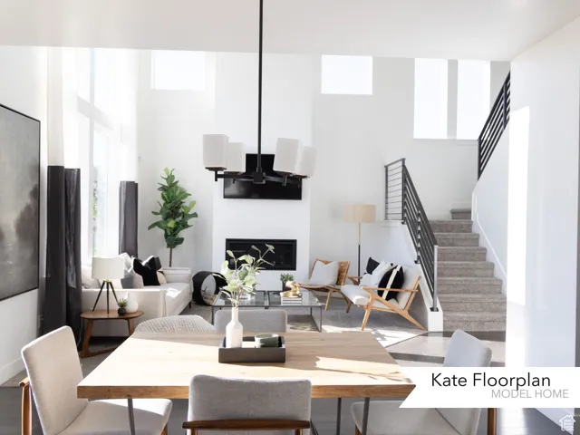 Living room with stairway, plenty of natural light, a high ceiling, and a glass covered fireplace