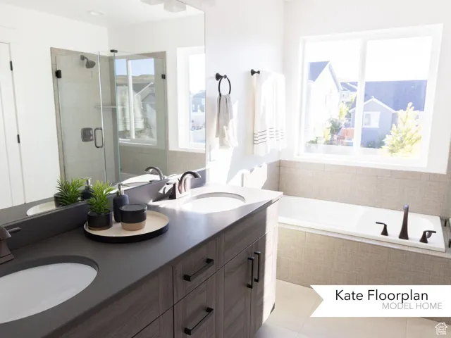 Bathroom featuring healthy amount of natural light, a garden tub, double vanity, and a stall shower