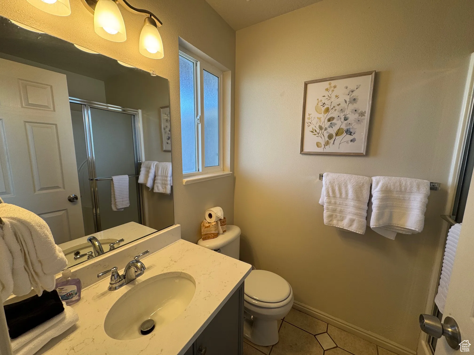 Bathroom with toilet, a shower stall, vanity, tile patterned floors, and baseboards