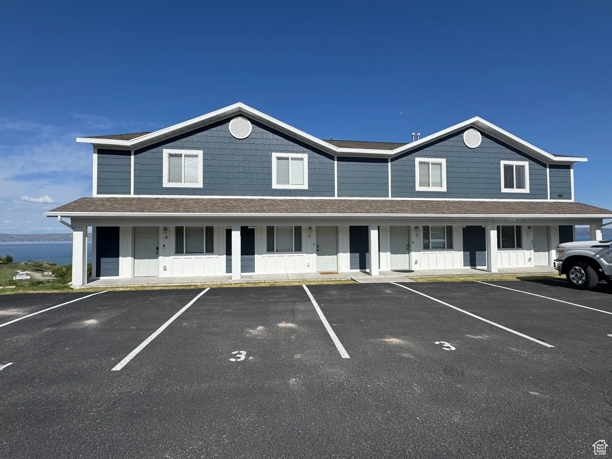 Townhome / multi-family property featuring uncovered parking, covered porch, and a shingled roof