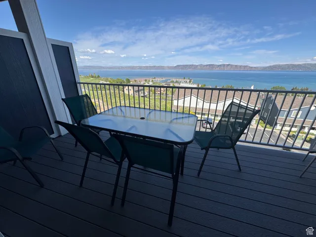 Wooden deck with a water and mountain view and outdoor dining area