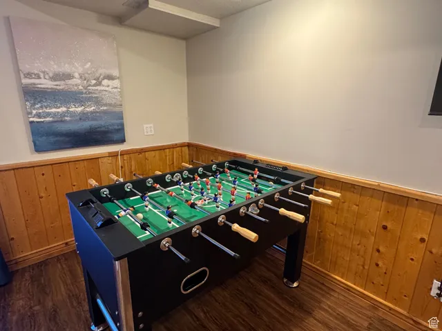 Game room featuring wainscoting, wood finished floors, and wood walls