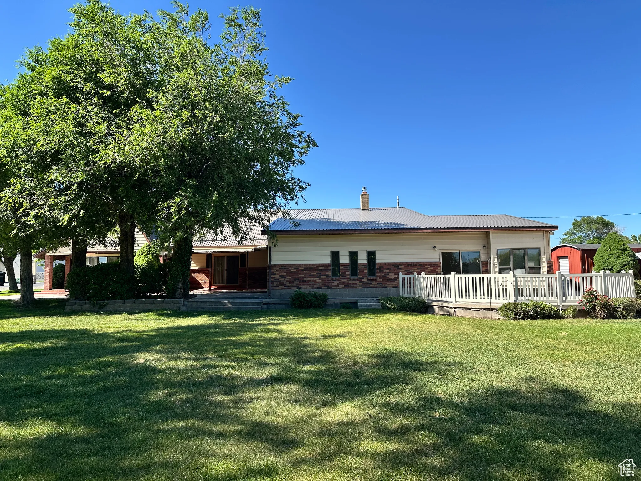 Rear view of property with a yard, brick siding, a deck, and a chimney