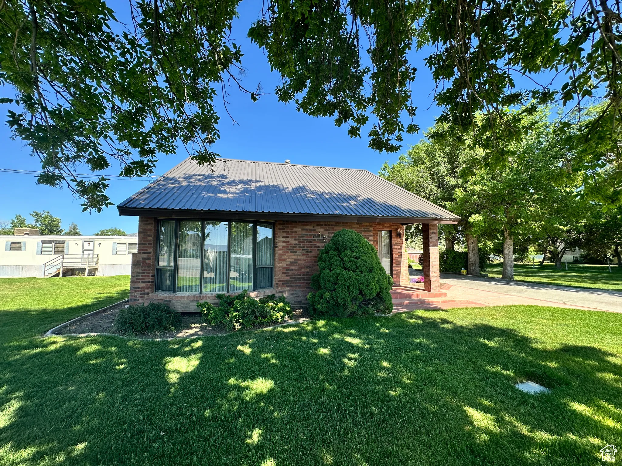 View of front of property featuring brick siding, a front lawn, and metal roof