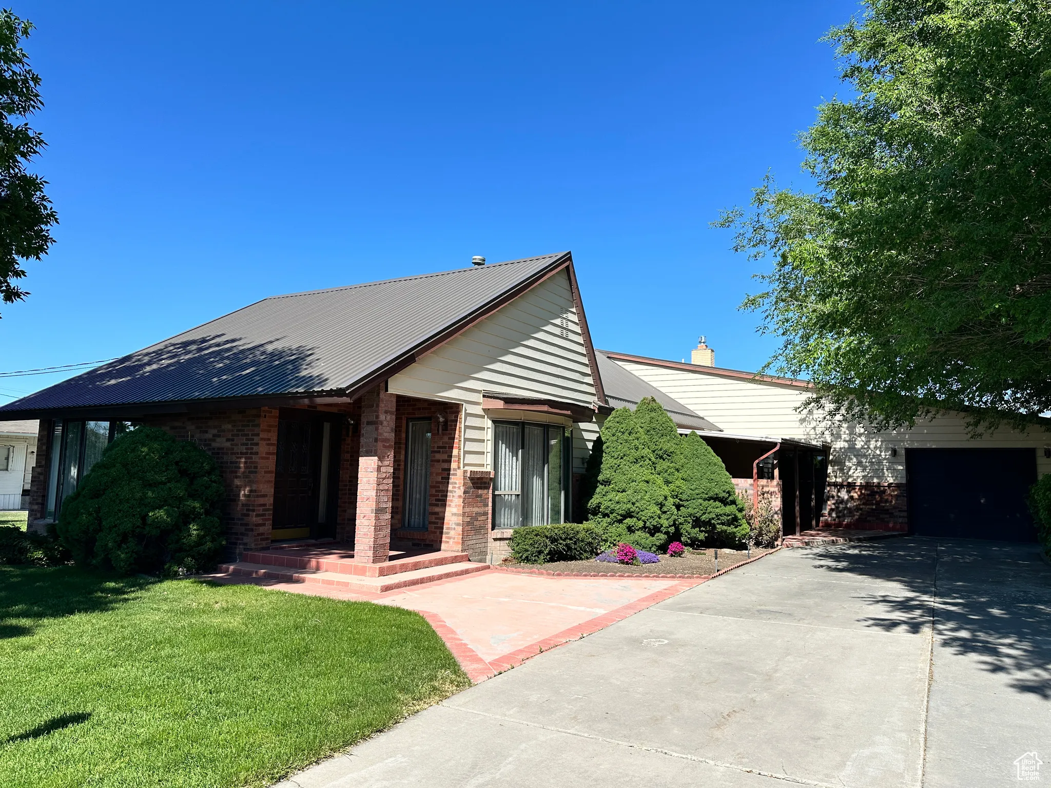 Ranch-style home featuring concrete driveway, a front yard, a garage, and brick siding