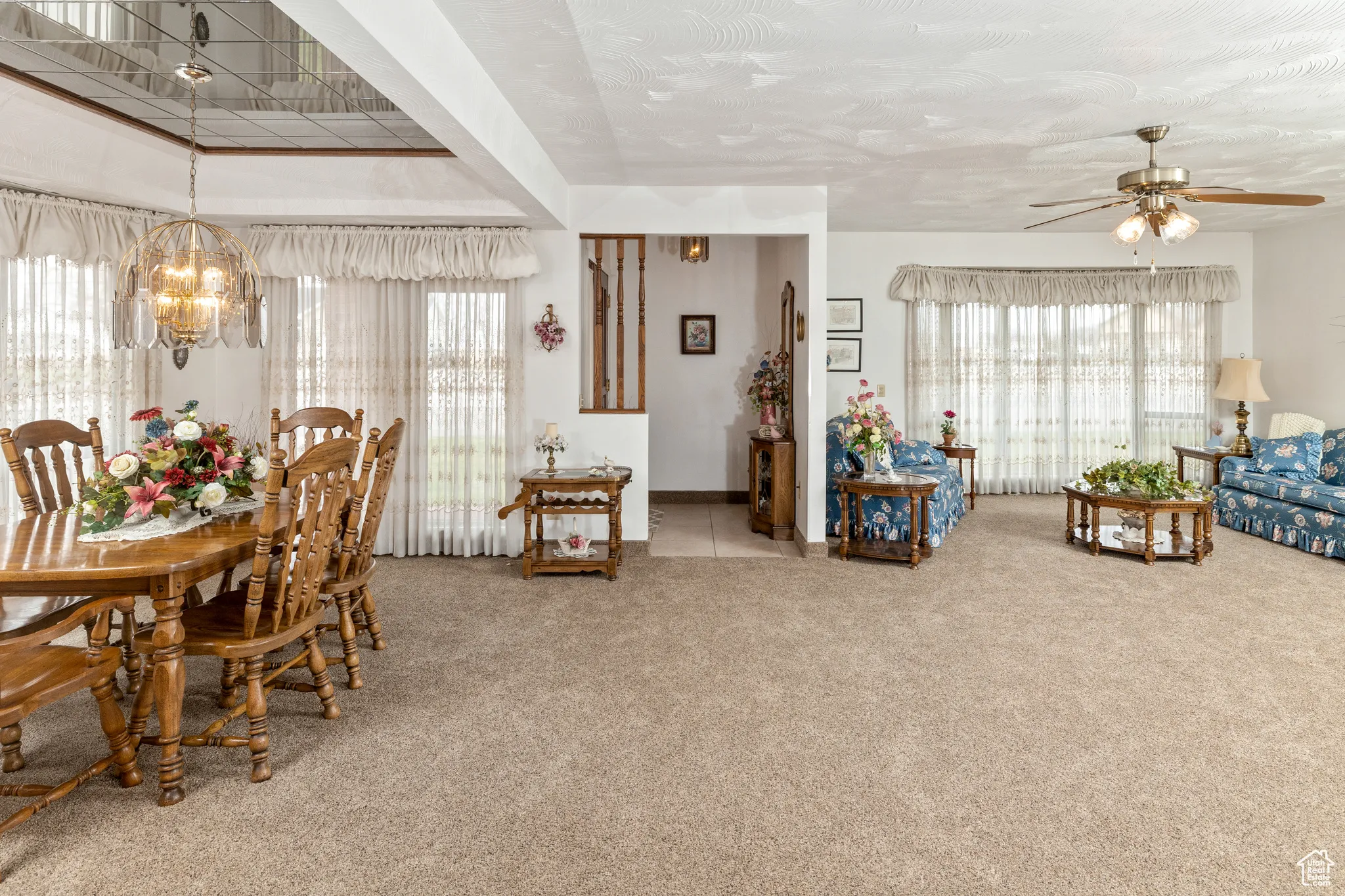 Carpeted dining room with a chandelier, healthy amount of natural light, a ceiling fan, and baseboards