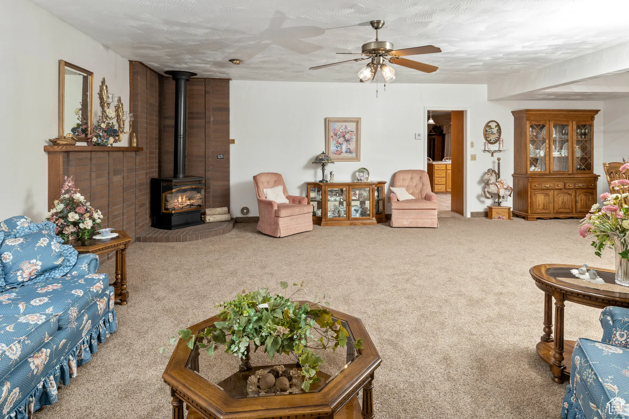 Carpeted living area featuring a wood stove and a ceiling fan
