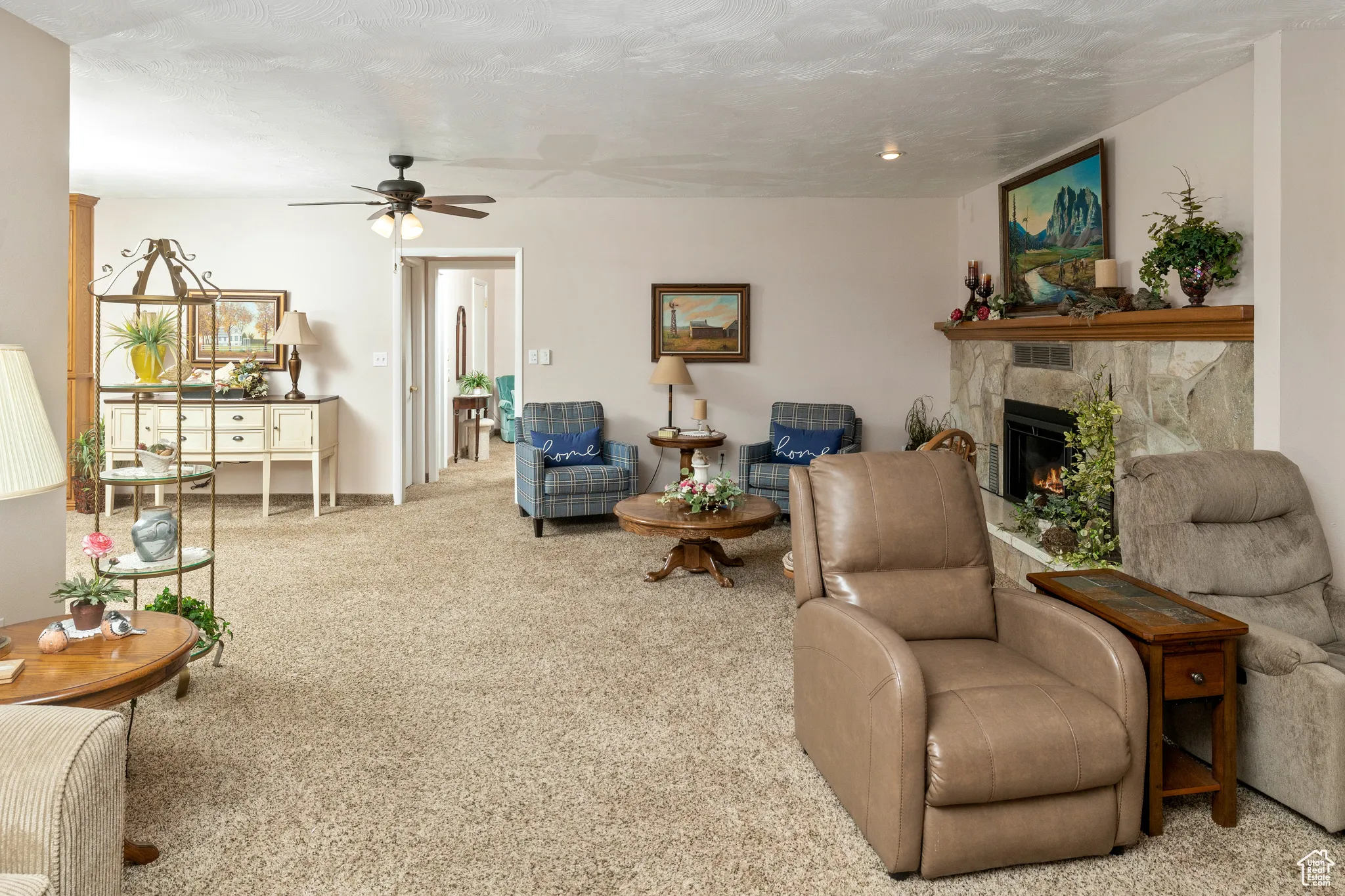Living room featuring a ceiling fan, a glass covered fireplace, and carpet flooring