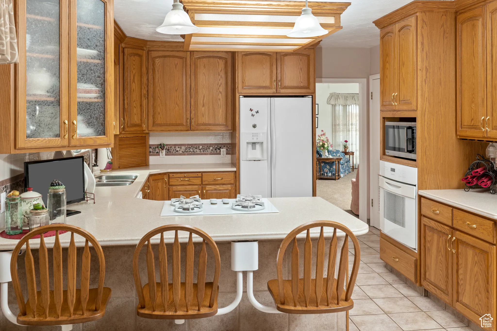 Kitchen featuring white appliances, light countertops, a sink, and glass insert cabinets
