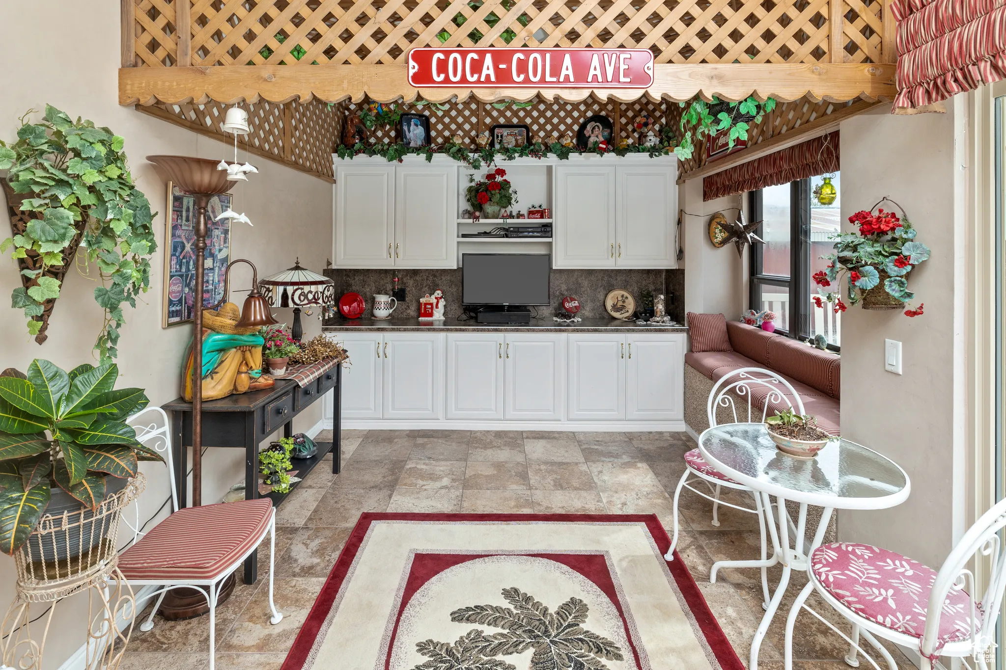 Kitchen with decorative backsplash, white cabinetry, light stone finish floors, and dark countertops