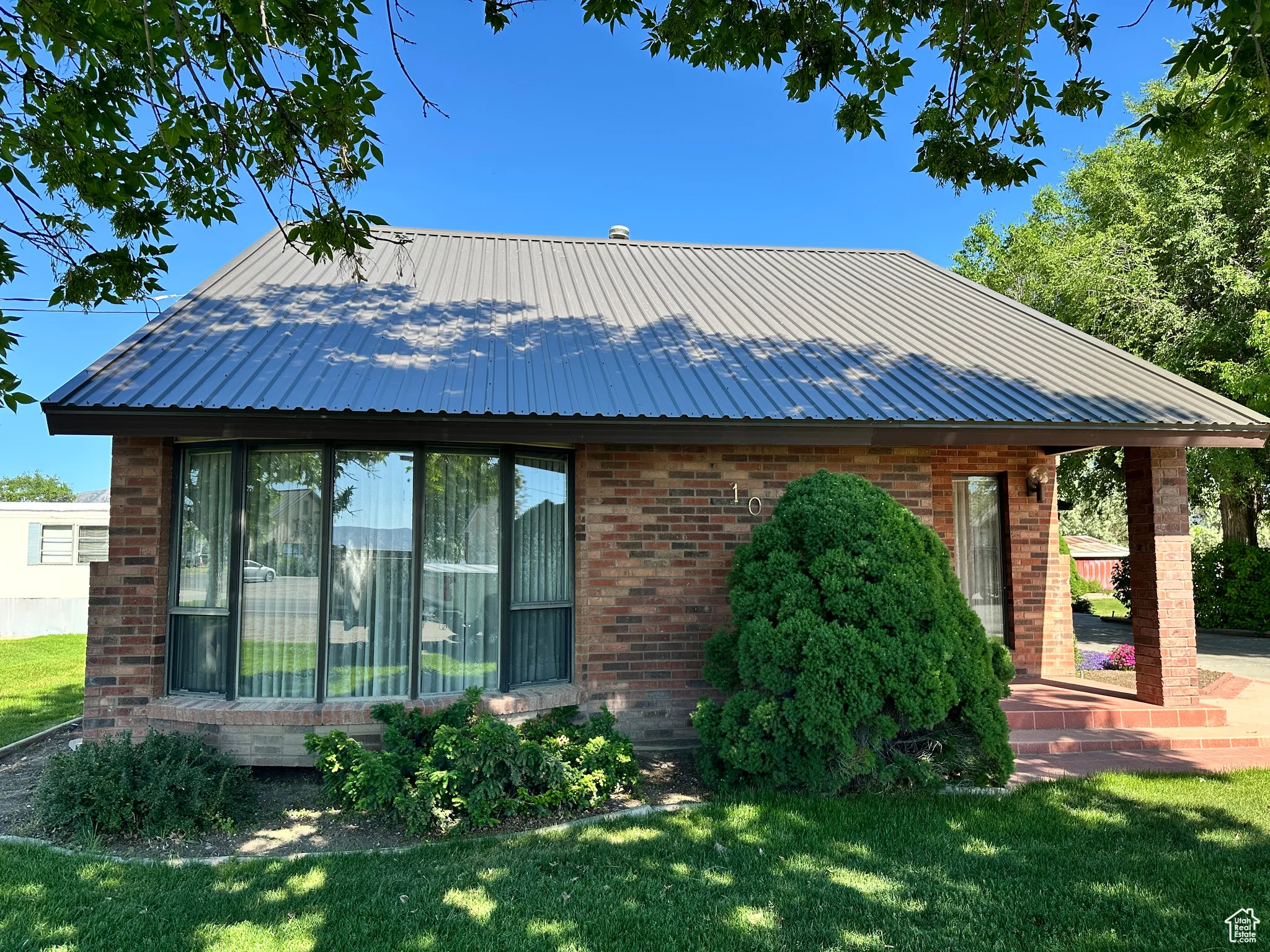 View of front of property with brick siding, a front lawn, and metal roof