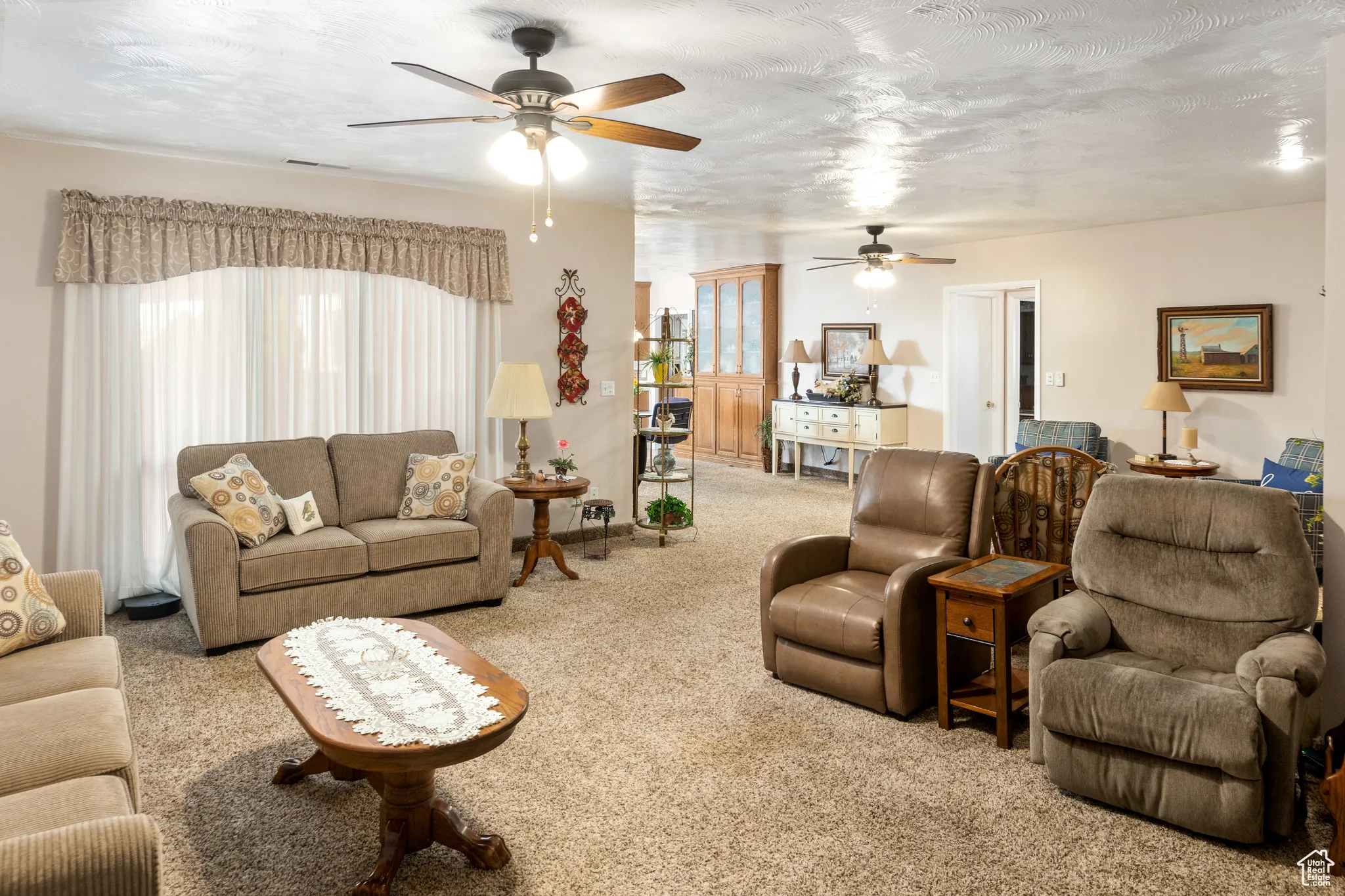 Carpeted living room with a ceiling fan and plenty of natural light