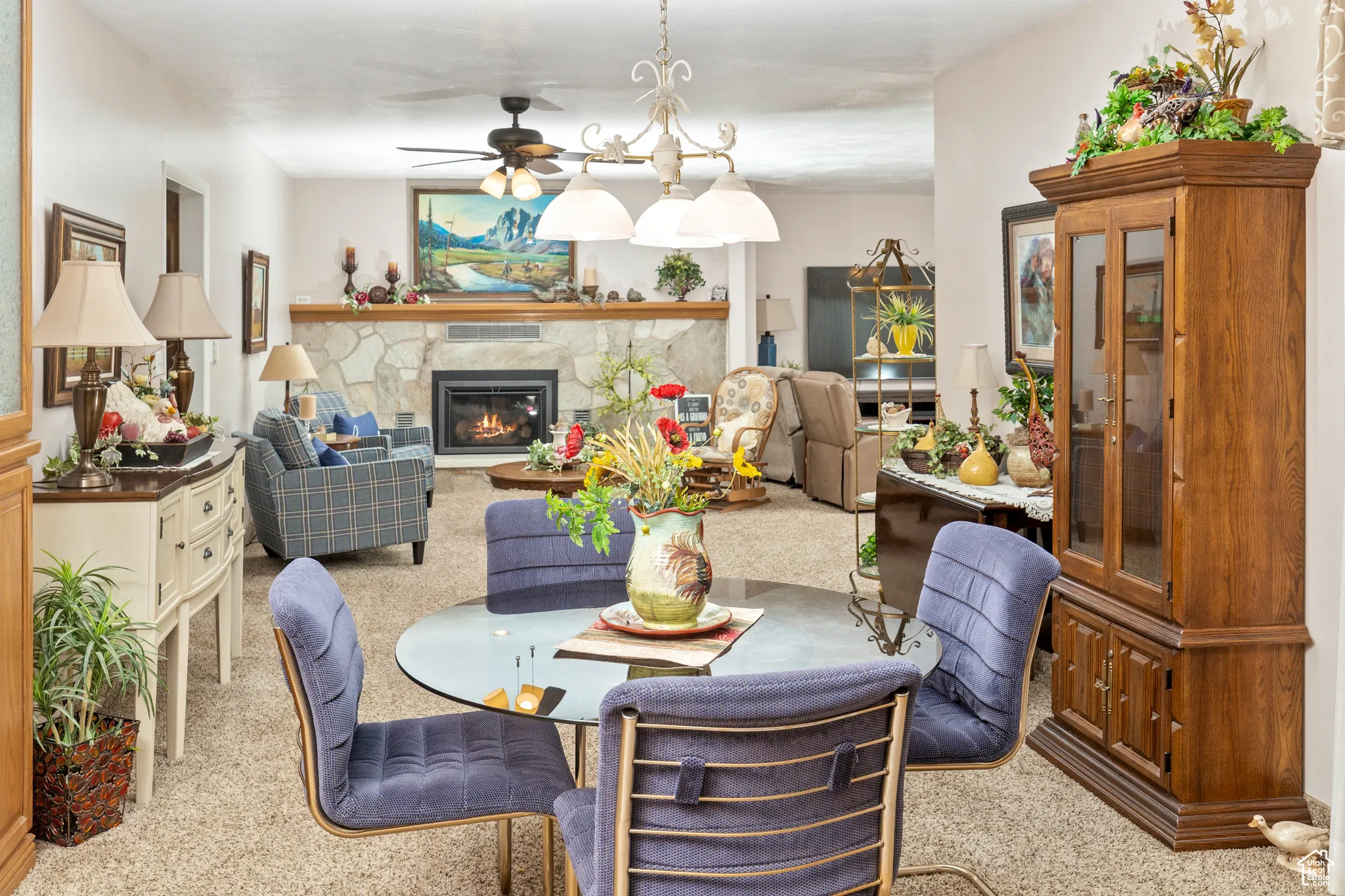 Dining area with carpet flooring, a ceiling fan, and a stone fireplace
