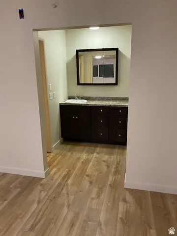 Hall with light wood-style flooring, baseboards, and a sink
