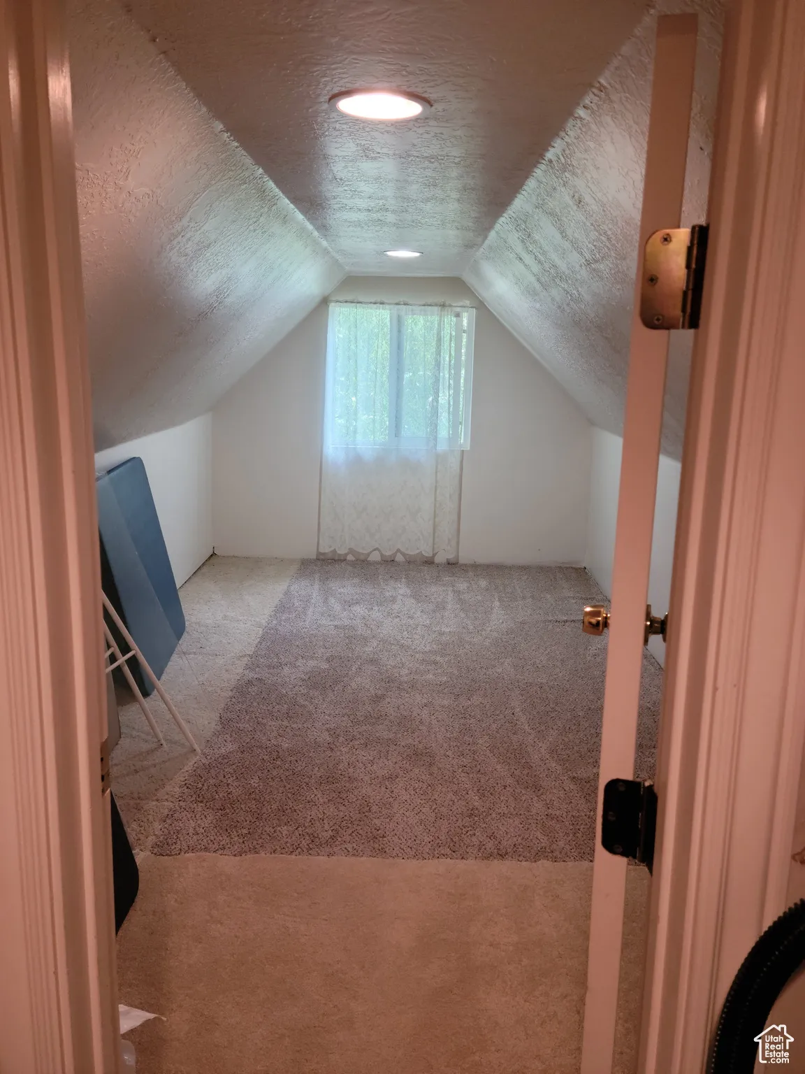 Bonus room with carpet flooring, a textured ceiling, and lofted ceiling