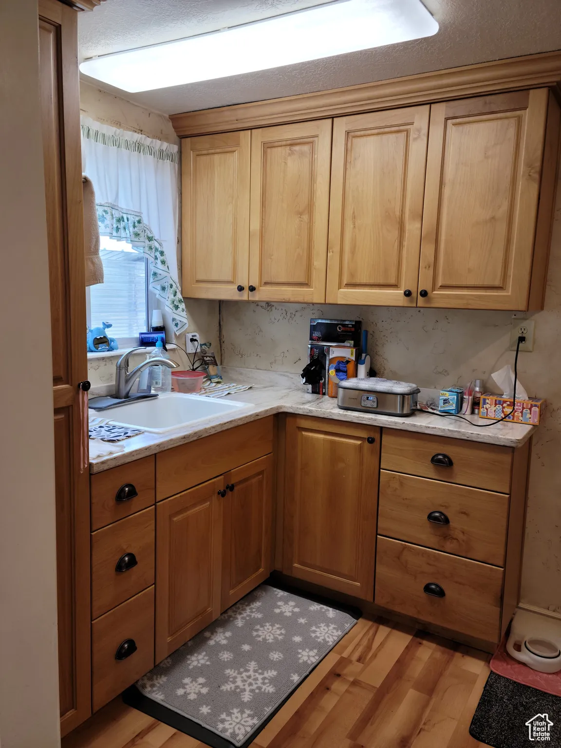 Kitchenette featuring a sink, light wood finished floors, and light countertops