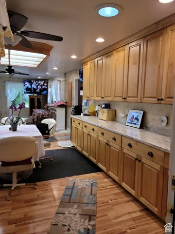 Kitchen featuring a ceiling fan, light wood-style flooring, open floor plan, recessed lighting, and light stone countertops