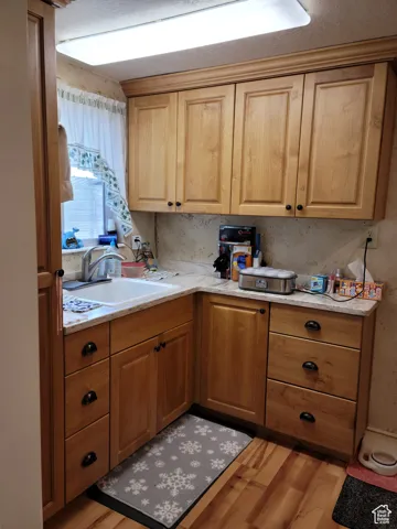 Kitchenette featuring a sink, light wood finished floors, and light countertops