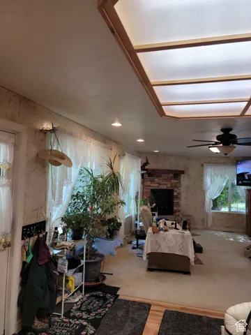 Living room with ceiling fan, a fireplace, and wood finished floors