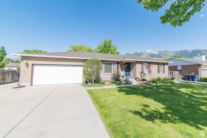 Single story home with brick siding, driveway, an attached garage, and a mountain view