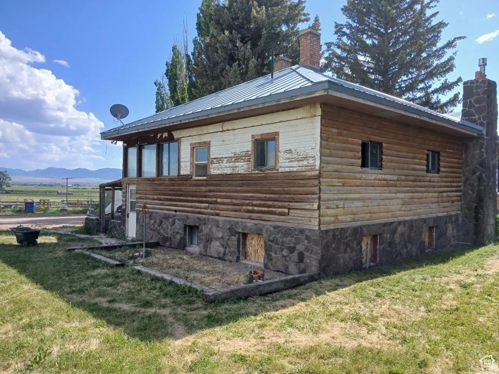 View of property exterior with a chimney, a yard, and a mountain view