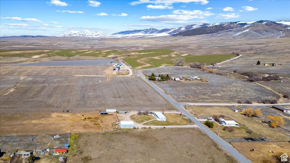 Aerial view of property and surrounding area featuring a mountain backdrop and rural landscape