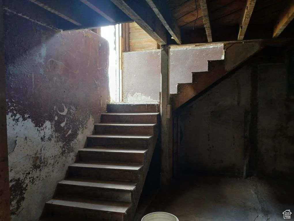 Staircase featuring unfinished concrete floors