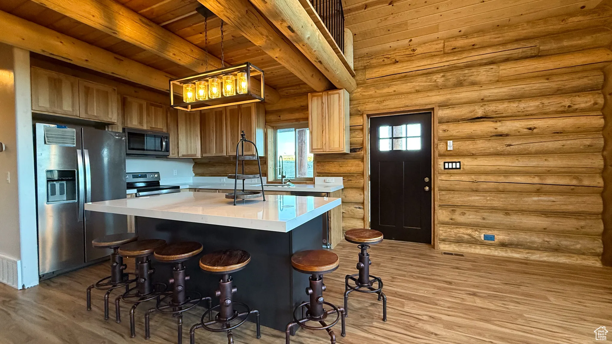 Kitchen featuring light countertops, stainless steel appliances, a center island, light wood-style floors, and pendant lighting