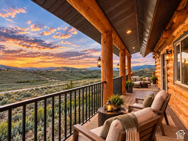 Expansive outdoor deck featuring log pillars, mounted lanterns, and a mountain and valley backdrop