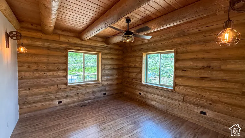 Room with wood ceiling with exposed beams, wood finished floors, ceiling fan, and log walls