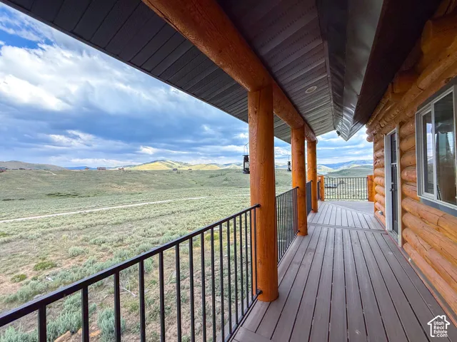 Covered deck featuring wood-finish flooring, log pillars, and black metal railings